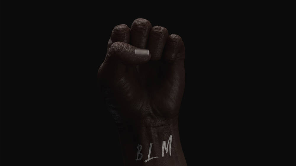 黑色的拳头在黑暗的背景下举起，手腕上写着BLM的字母