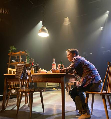 演员坐在舞台上的一张桌子旁